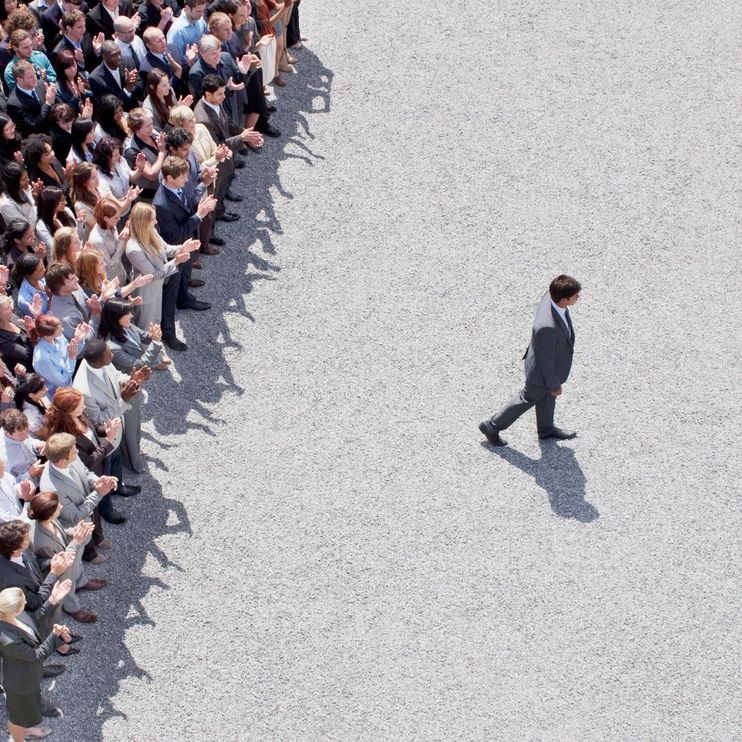 Businessman walking away from a crowd, and being applauded for it,.